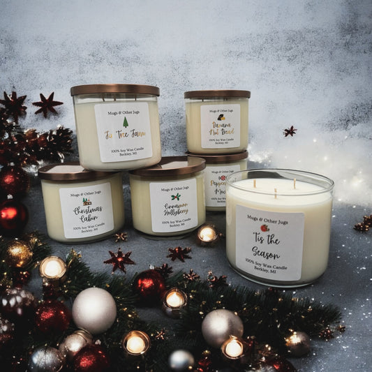 A collection of candles with holiday decorations, each candle has a label with different scent names such as Banana Nut Bread, Peppermint Mocha, Cinnamon Hollyberry, and others. The candles are presented in clear glass jars with bronze lids.