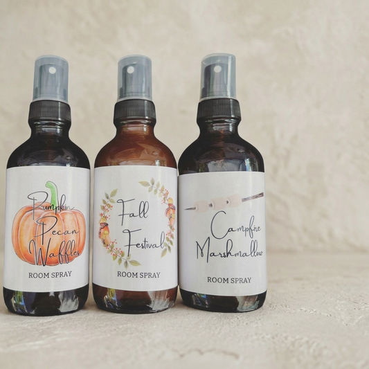 Three room spray bottles with labels on a textured beige background